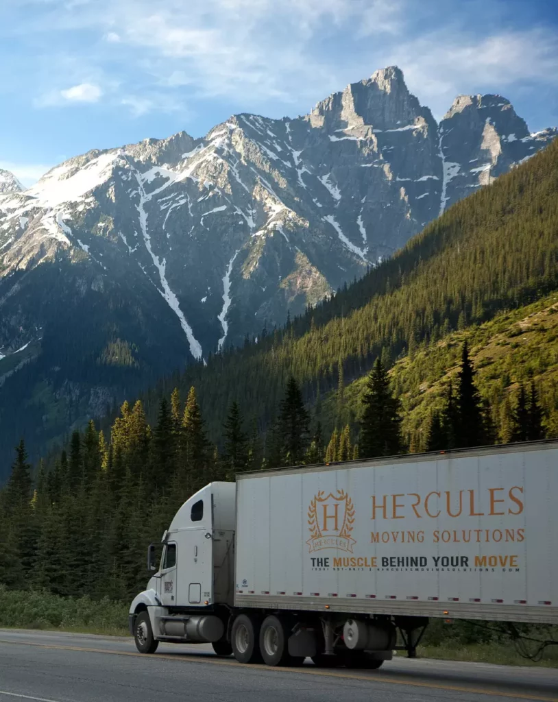Hercules Moving Solutions - Long Distance Relocation - Truck Driving into Mountain Landscape