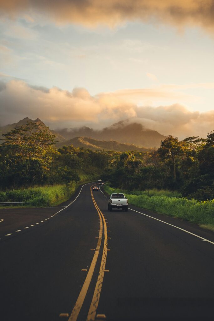 Sunset drive through a mountain road in Hawaii surrounded by tropical greenery.