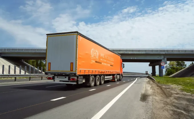 Freight truck driving on an open highway under a blue sky, representing long-distance moving and transportation services.